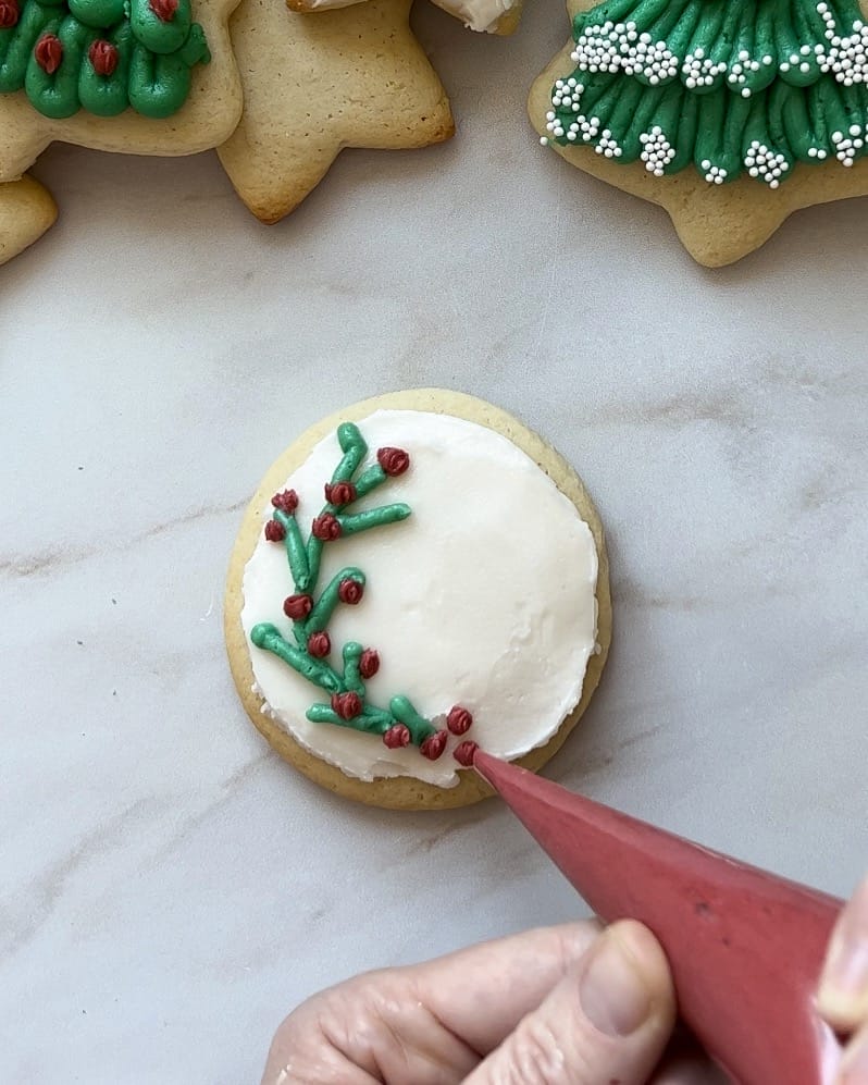 Round sugar cookie decorated with frosting like holly and berries.