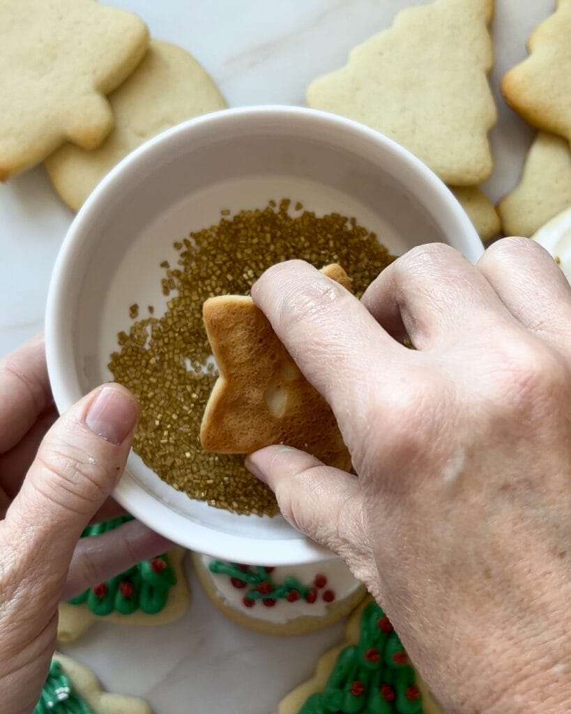 Dipping a star shaped sugar cookie in sprinkles.