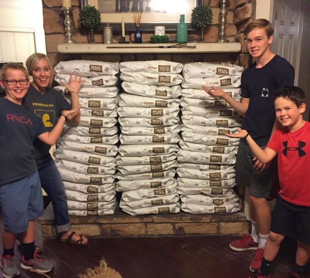 Heather and kids with bags of stacked flour.
