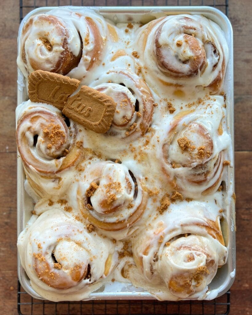 A pan of biscoff cinnamon rolls with a cookie on top.