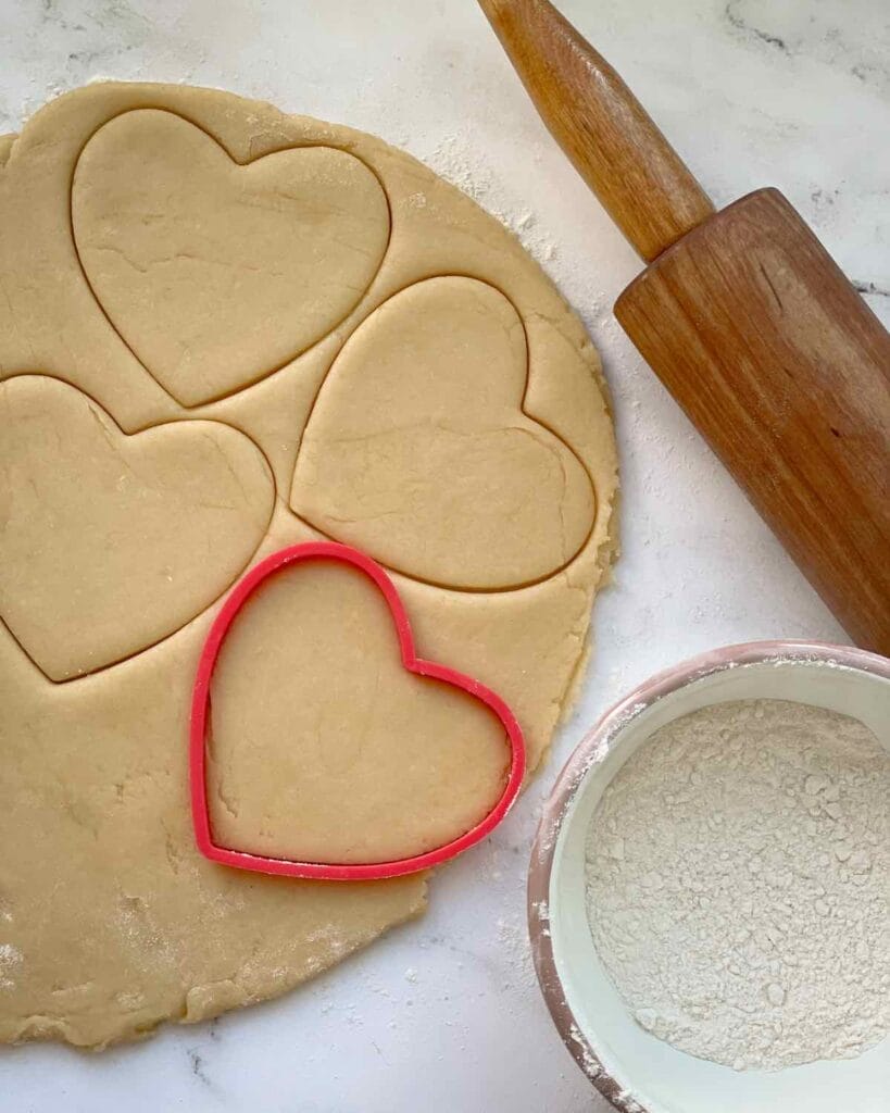 Sugar cookie dough with hearts cut out.