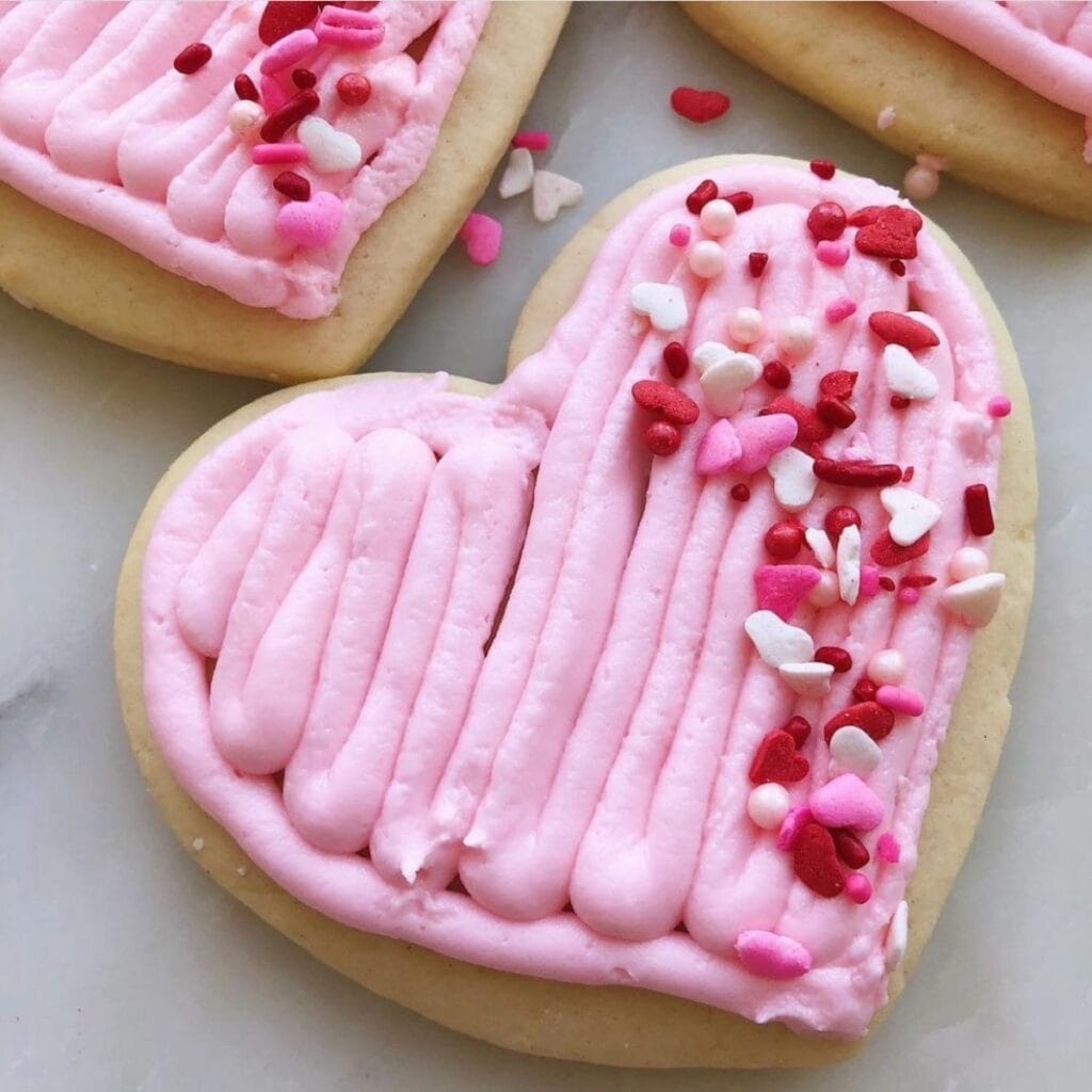 Heart shaped sugar cookies with pink frosting and red, pink and white sprinkles