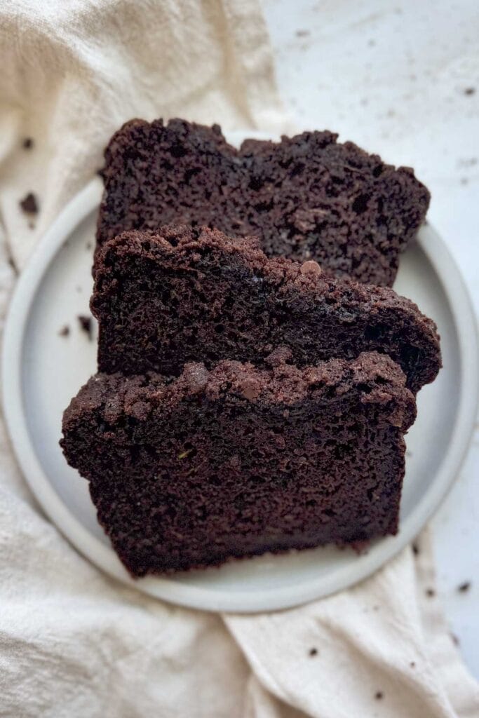 Three slices of double chocolate zucchini bread on a white plate.