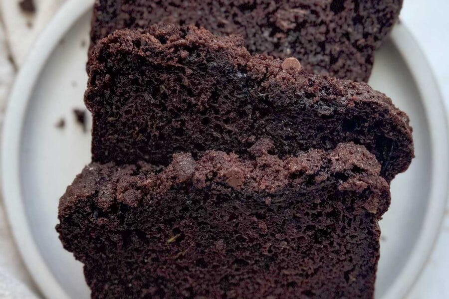 Three slices of double chocolate zucchini bread on a white plate.